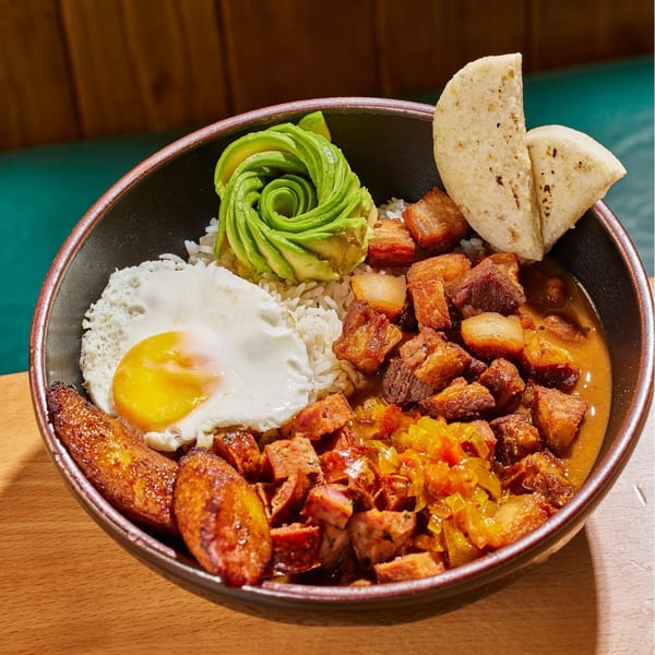 A Colombian bandeja paisa with rice, fried egg, plantains, avocado, pork belly, and sausage.